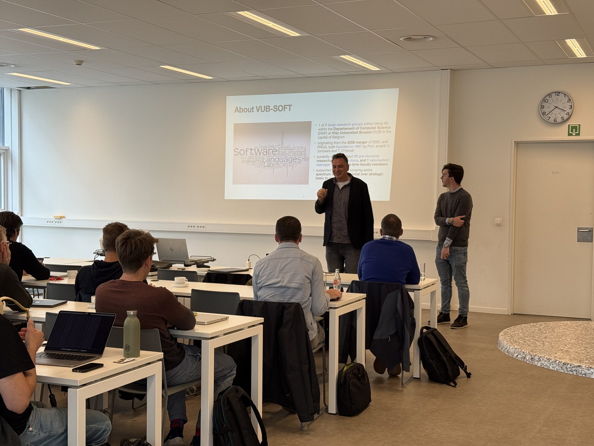 A speaker introduces the lab to an audience of students and professionals, in front of a slide titled "About VUB-SOFT"